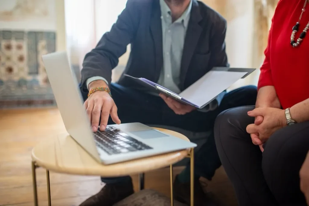 Beraterin und Berater besprechen Unterlagen am Laptop, Symbolbild für die unabhängige Beratung zur Berufsunfähigkeitsversicherung