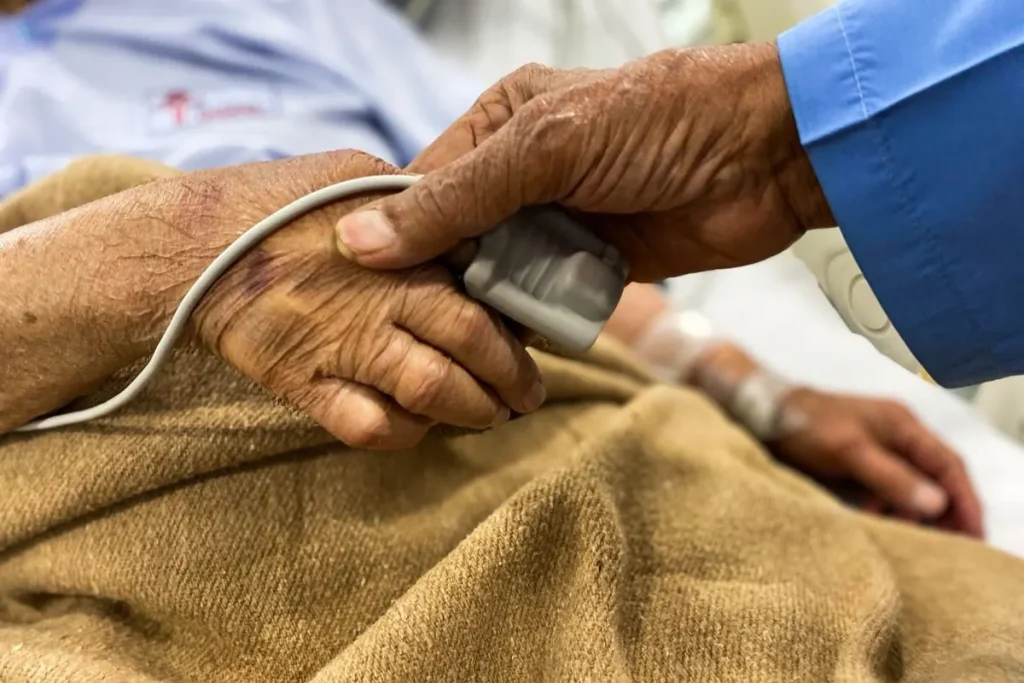 Pflegende Hand hält die Hand eines älteren Menschen, Symbolbild für Pflegevorsorge und Absicherung im Pflegefall