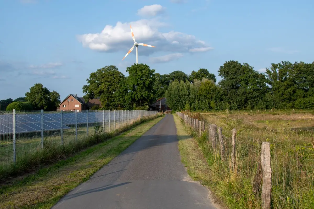 Ländliche Landschaft mit Solarpark und Windrad am Feldweg als Sinnbild für erneuerbare Energie
