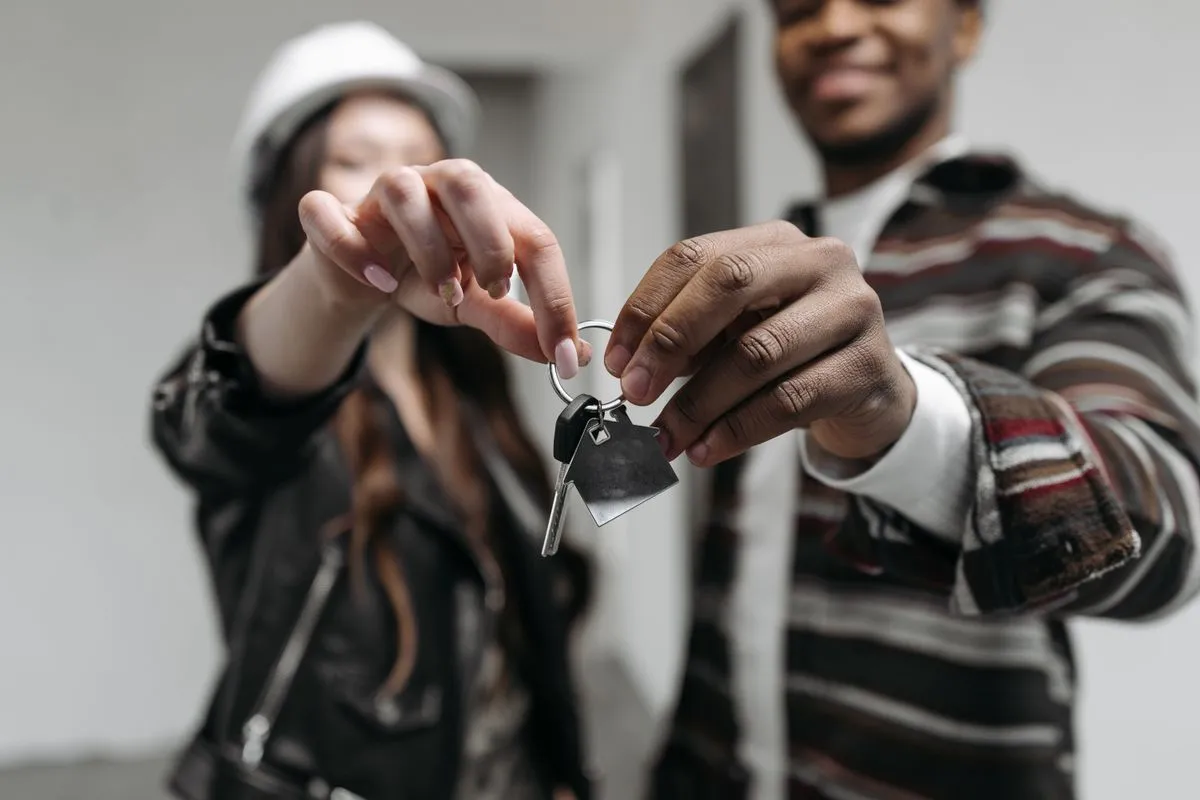Glückliches Paar hält die Schlüssel mit Haus-Anhänger für das neue Zuhause in der Hand